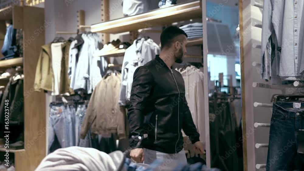 Male Customer Trying Out Leather Jacket and Looking into Mirror. Male Customer Trying Out Leather Jacket and Looking into Mirror.