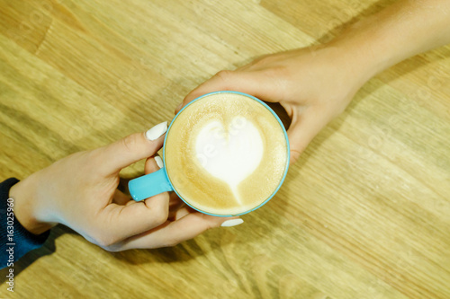 Human feelings. Frothy cappuccino between two hands. Friendship pastime