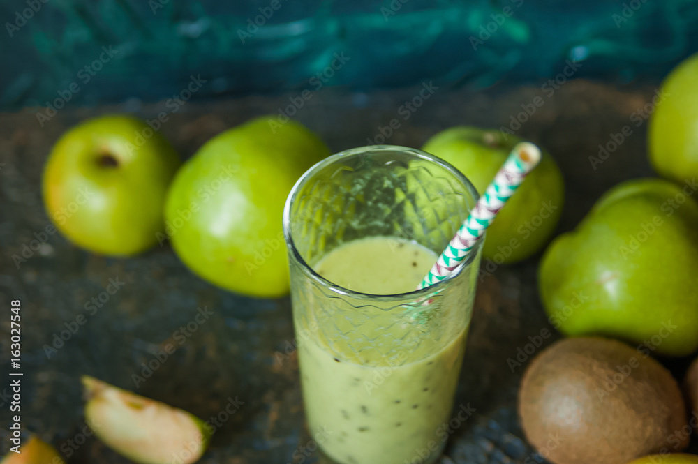 Fototapeta premium Green apples and kiwi on a wooden tray on a dark textural background. A glass of apple juice with a straw. A glass of kiwi juice with a straw. Healthy eating. Fruits, detox