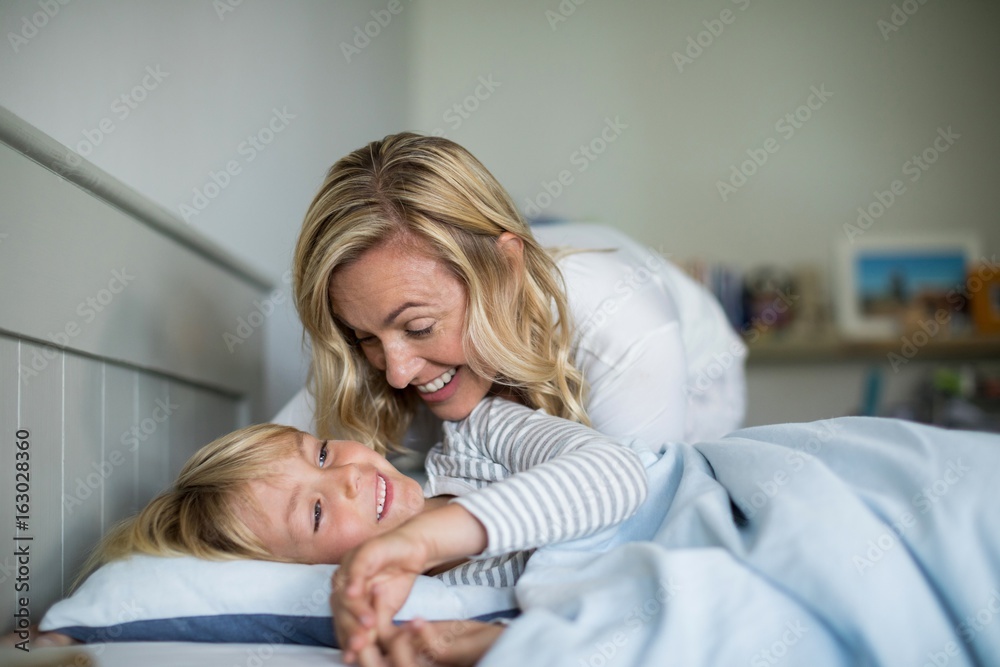 Fototapeta premium Mother and son having fun together in the bedroom