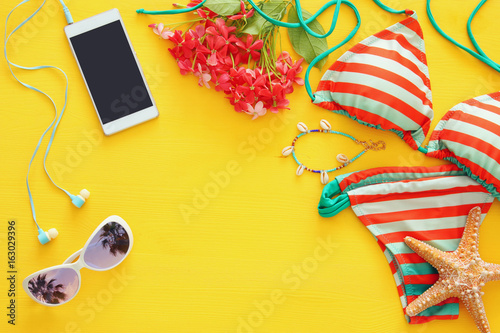 Top view of fashion female swimsuit bikini on yellow wooden background