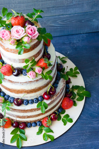 Naked wedding cake decorated with berries and flowers