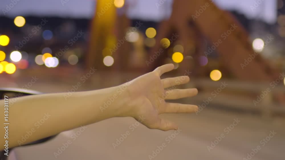 Young Woman Holds Her Hand Out Moving Car Window, Feels The Breeze, On Bridge At Night (Slow Motion) Young Woman Holds Her Hand Out Moving Car Window, Feels The Breeze, On Bridge At Night (Slow Motion)