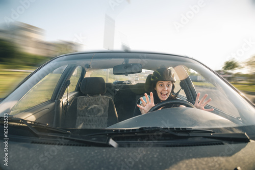 woman driving car in helmet with horror on her face