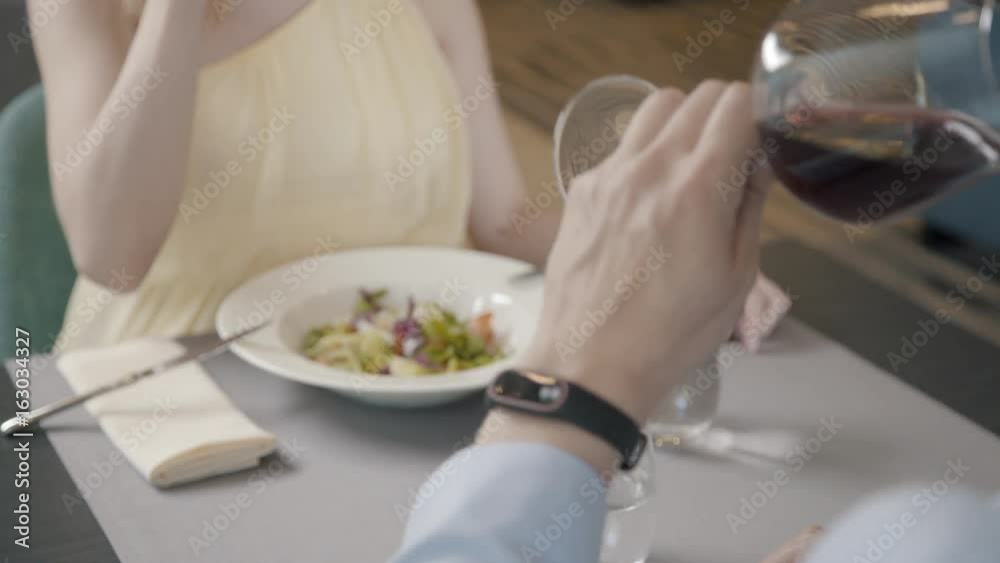 A romantic dinner in a restaurant: a man in a suit and a woman in a beautiful dress are sitting at a table and clinking glasses of wine. Toast for love: clink glasses of wine. Married couple. A romantic dinner in a restaurant: a man in a suit and a woman in a beautiful dress are sitting at a table and clinking glasses of wine. Toast for love: clink glasses of wine. Married couple.