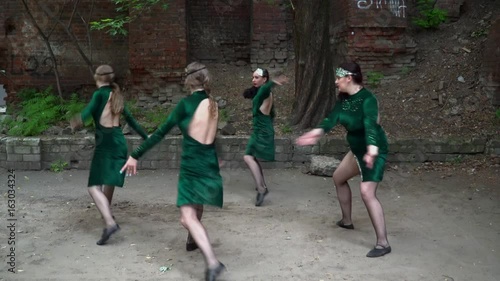 Group of young women in green costumes dancin in the yard photo