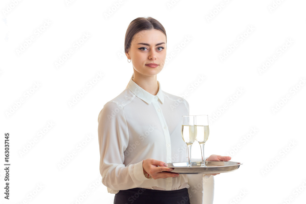 charming young waitress looks straight and holds a tray with glasses of champagne charming young waitress looks straight and holds a tray with glasses of champagne