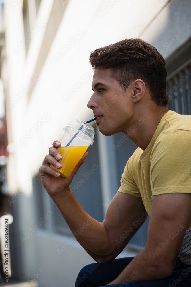 Side view of young man drinking juice Side view of young man drinking juice