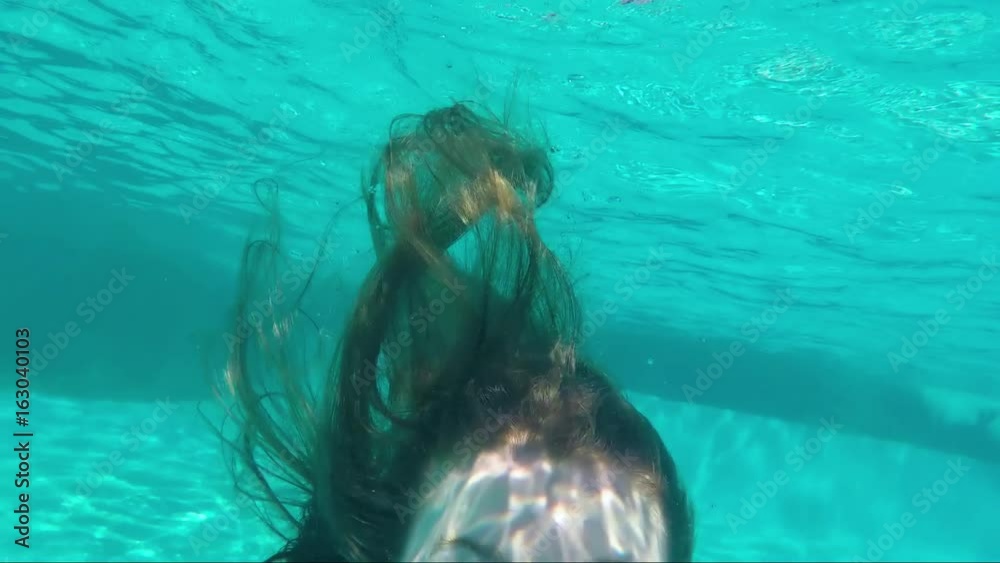 Happy Teen Girl Swims In Resort Pool, She Takes A Deep Breath, Then Poses With A Smile Underwater, Then Goes Up For Air