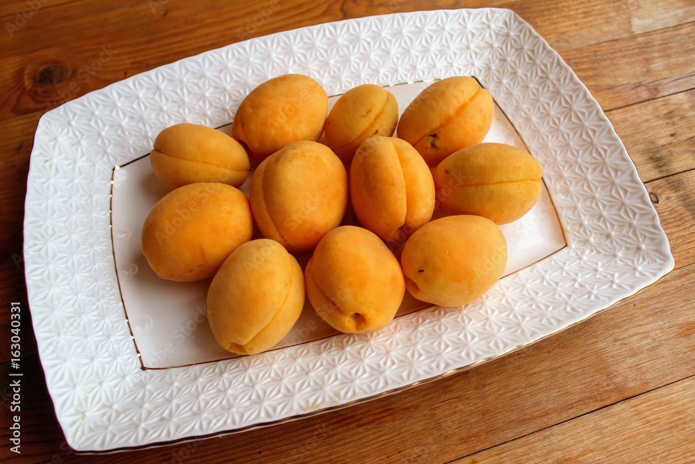 Fresh apricots are a group and individually on the plate and in a human hand. Fresh apricots are a group and individually on the plate and in a human hand.