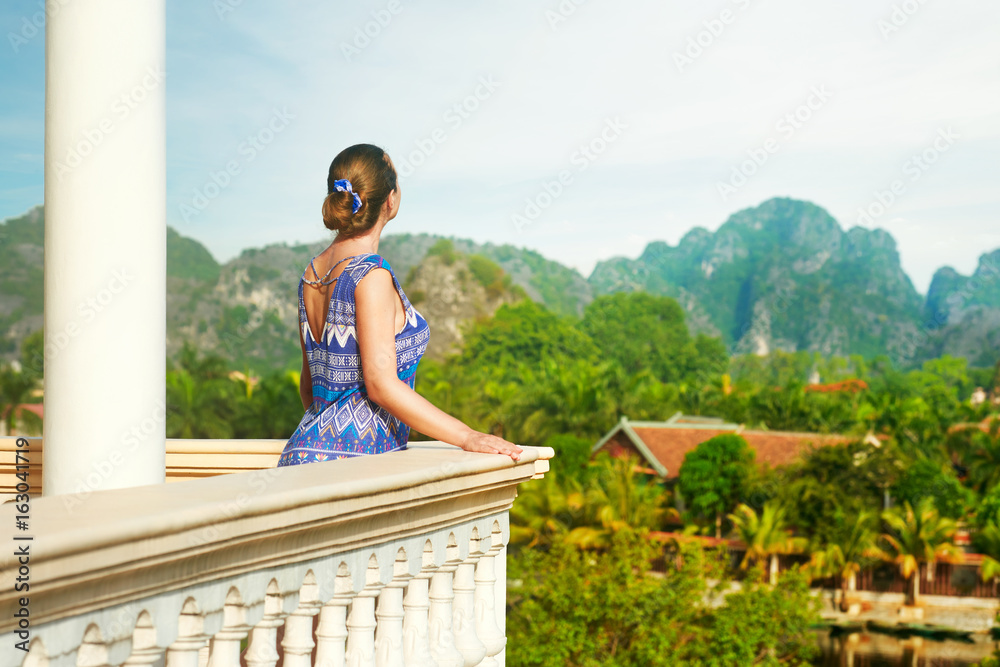 Woman standing on the balcony watching beautiful mountains view.