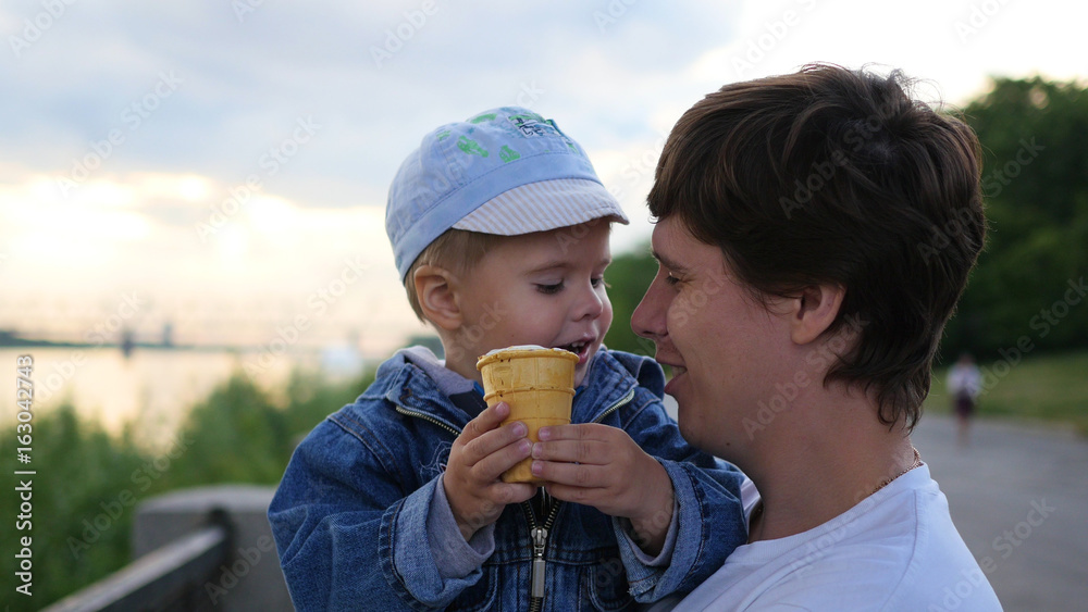 the child and the father is eating in a waffle Cup ice cream closeup. Family festival in the Park the child and the father is eating in a waffle Cup ice cream closeup. Family festival in the Park