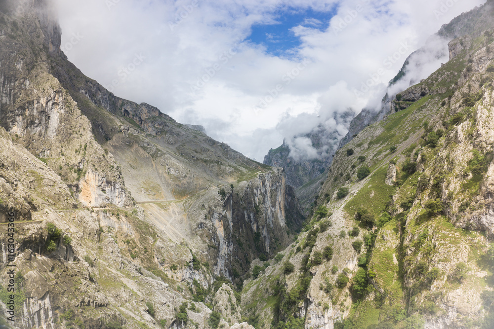 Fototapeta premium Beautiful landscape of the mountains in Picos de Europa in Spain; hiking trail in foggy and cloudy summer day