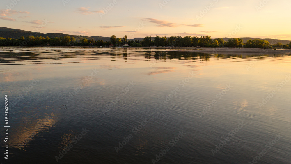 summer beach sunset. beauty sunset by river in summertime. reflection of clouds on water in sunset