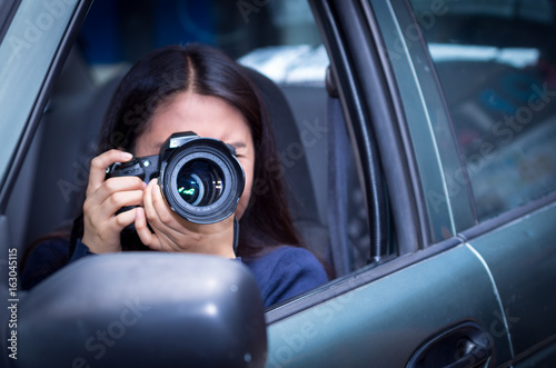 Young woman stalking and taking pictures with her camera, inside of her car © Fotos 593