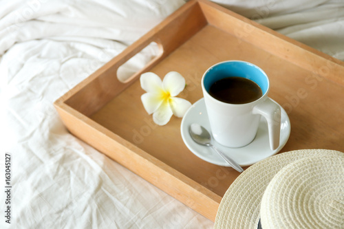 coffee cup in wood tray on the bed background in the morning time.