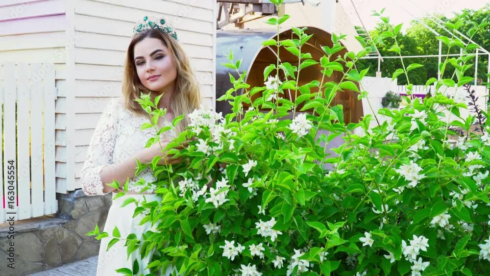 Young bride smels flowers on the bush during the summer Young bride smels flowers on the bush during the summer