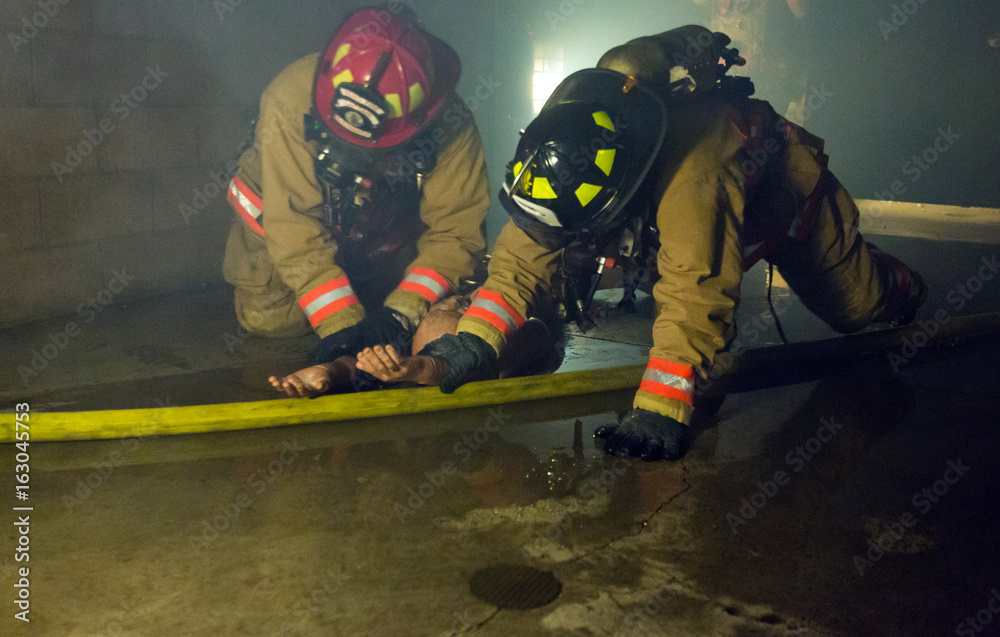 Fototapeta premium Firefighter training exiting the building with a victim