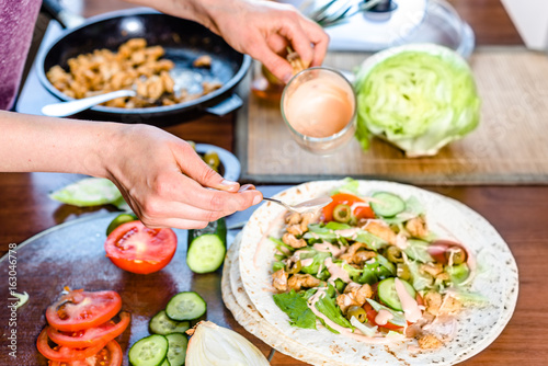 Fast food cooking. Hands preparing tortilla wrap with chicken and vegetable salad  kebab gyros filling.