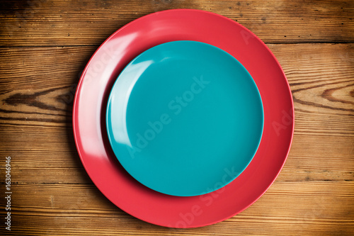 Platos redondo azul y rosa sobre fondo de mesa de madera rústica. Vista cenital