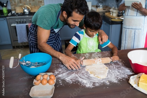 High angle view father assisting son for rolling dough
