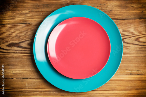 Plato redondo rosa y azul sobre fondo de mesa de madera rústica. Vista cenital
