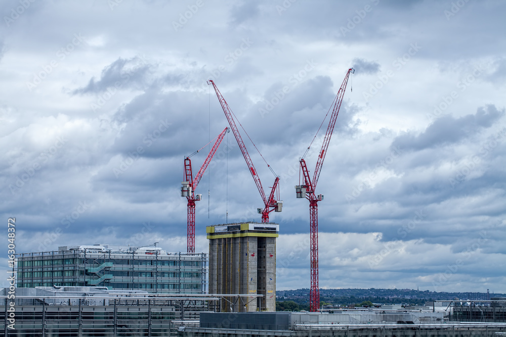 High rise building construction with red cranes over London.