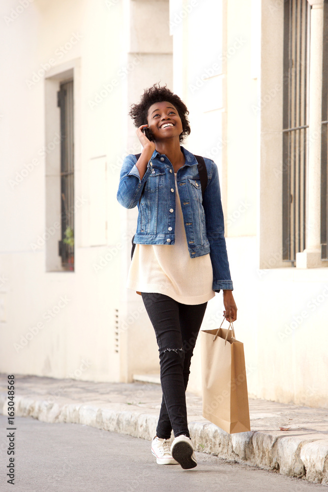 African woman walking on the street with shopping bags and mobile phone African woman walking on the street with shopping bags and mobile phone