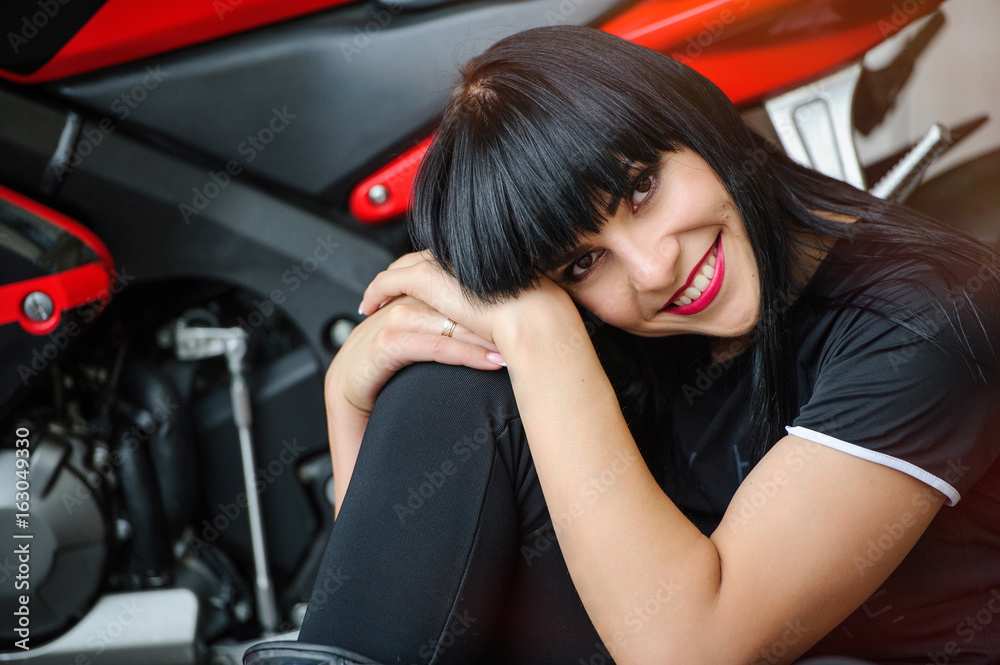 Freedom and style. Bright portrait of a young woman with a red motorcycle. Girl biker sits in front of a motorcycle Freedom and style. Bright portrait of a young woman with a red motorcycle. Girl biker sits in front of a motorcycle