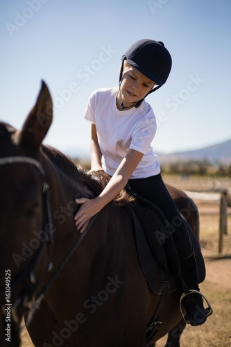 Rider girl caressing the horse in the ranch