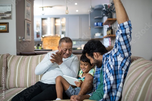 Happy grandfather and father with boy sitting on sofa