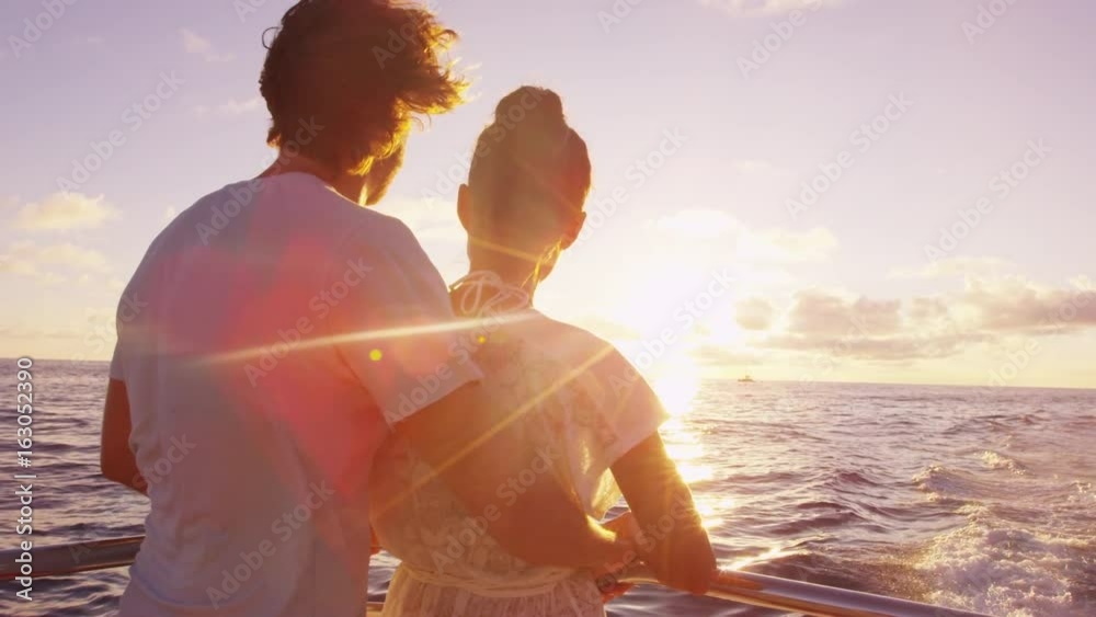 Cruise ship vacation couple enjoying sunset view sailing on small cruise boat at sea. Romantic couple on honeymoon travel at sea looking at sunset. RED EPIC SLOW MOTION.