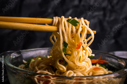 Noodles with vegetables on a wooden background