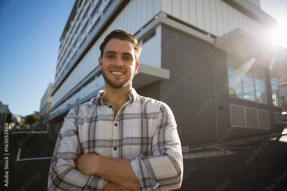 Smiling man with arms crossed standing by building in city Smiling man with arms crossed standing by building in city