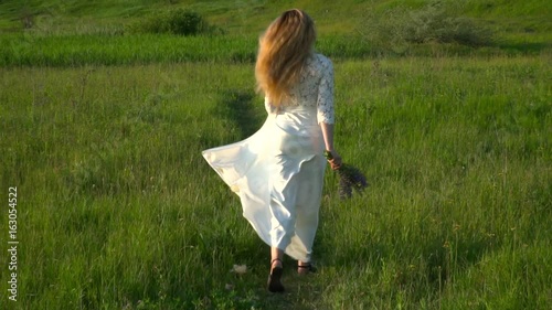 Beautiful woman in white dress running on the meadow slow motion