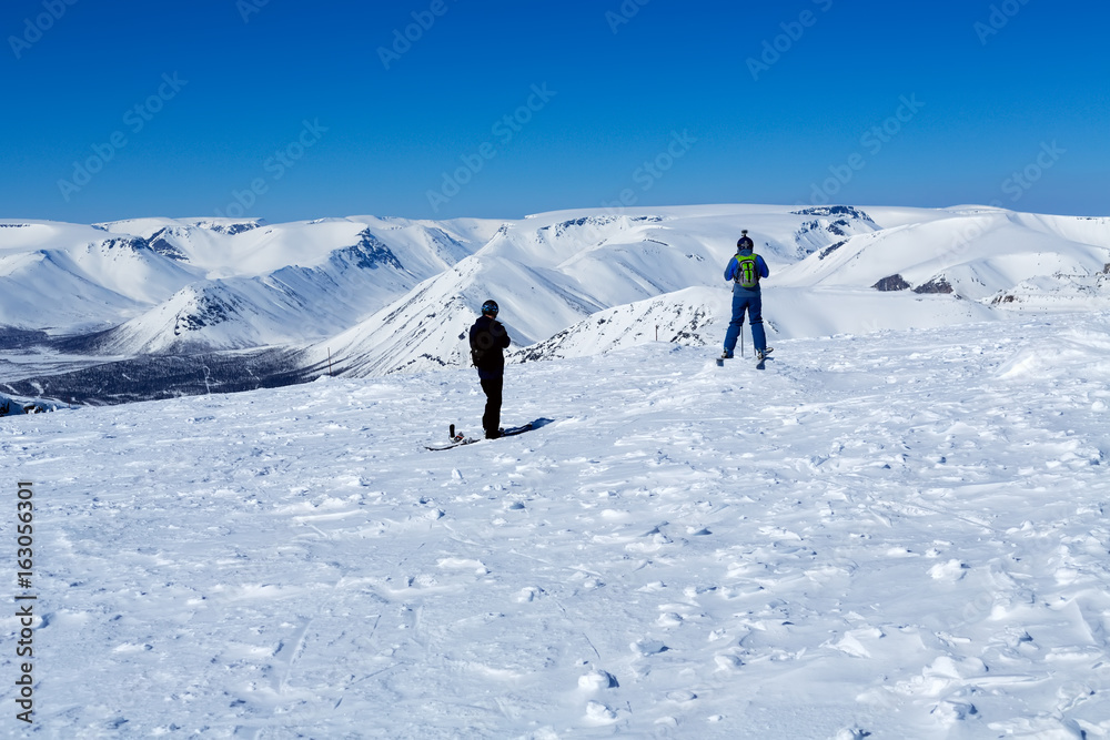 Two snowboarders at the top of the mountain