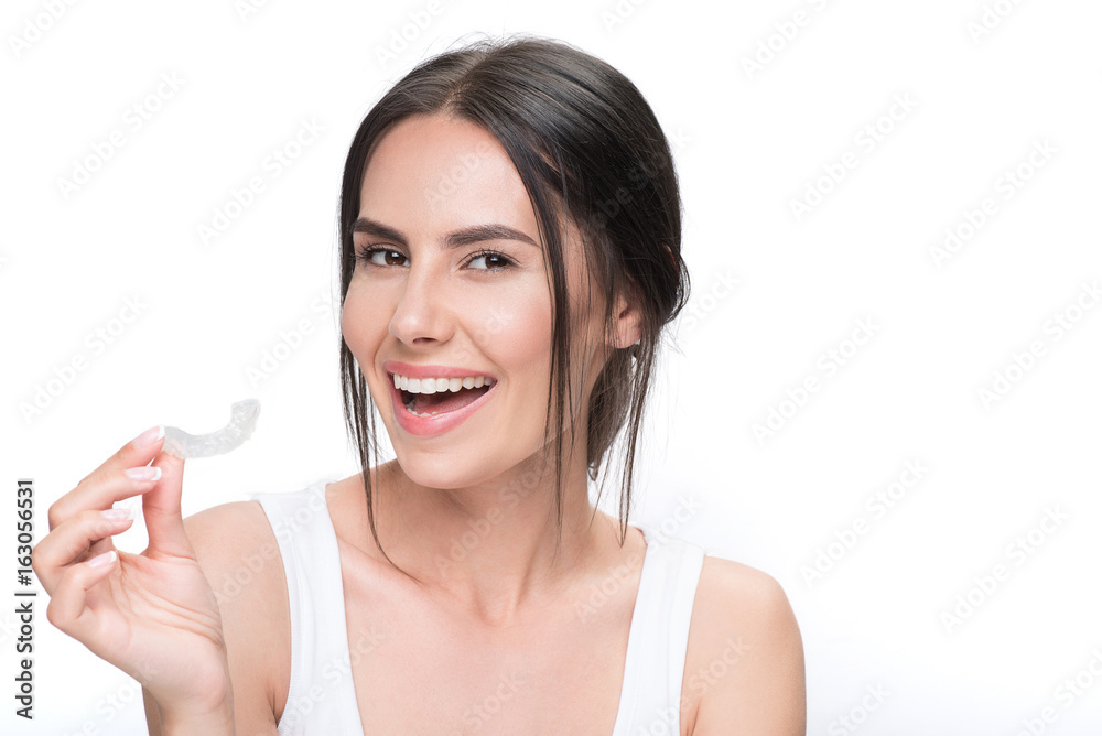 Cheerful young woman showing clear aligner Cheerful young woman showing clear aligner