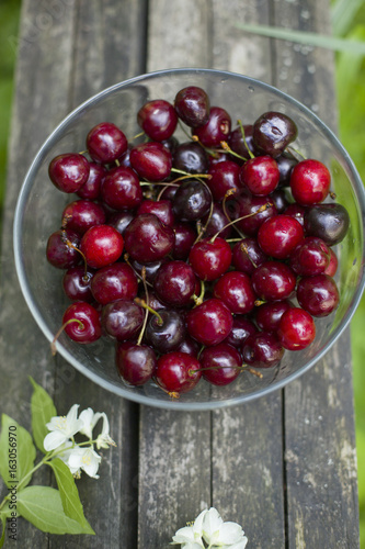  a bowl with fresh red cherry berries on old wooden background