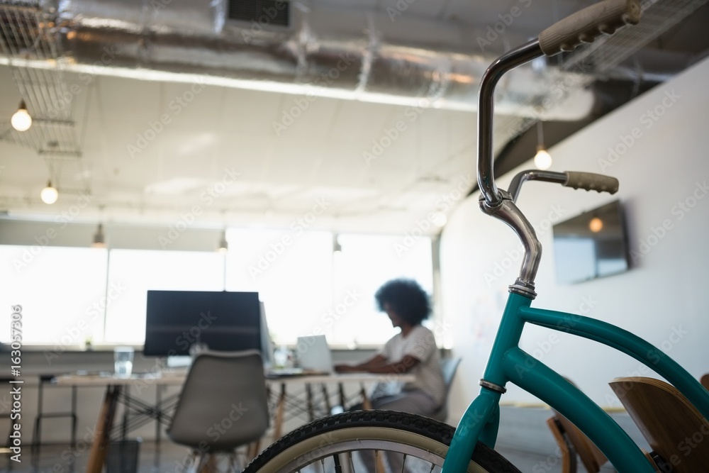Fototapeta premium Close-up of bicycle with man working in background at office