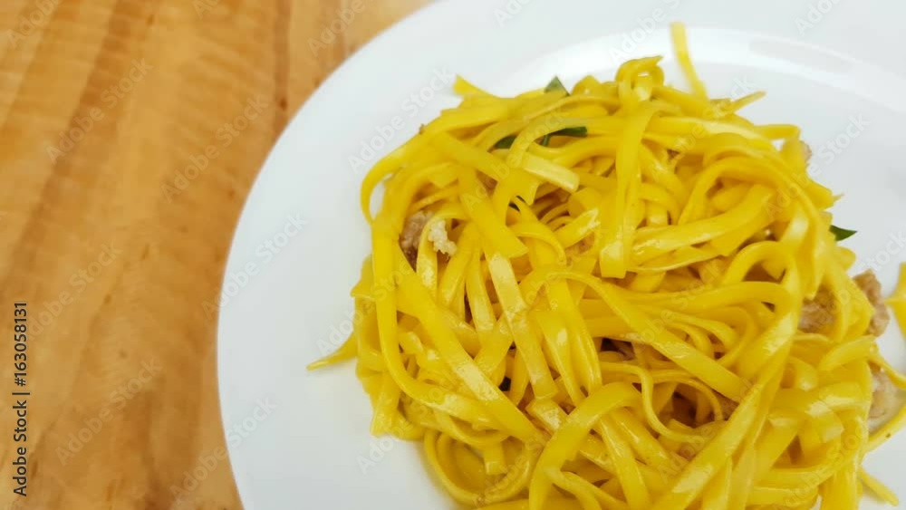 Yellow noodles on white plate and white measure tape on wooden background. Dolly from left to right Yellow noodles on white plate and white measure tape on wooden background. Dolly from left to right