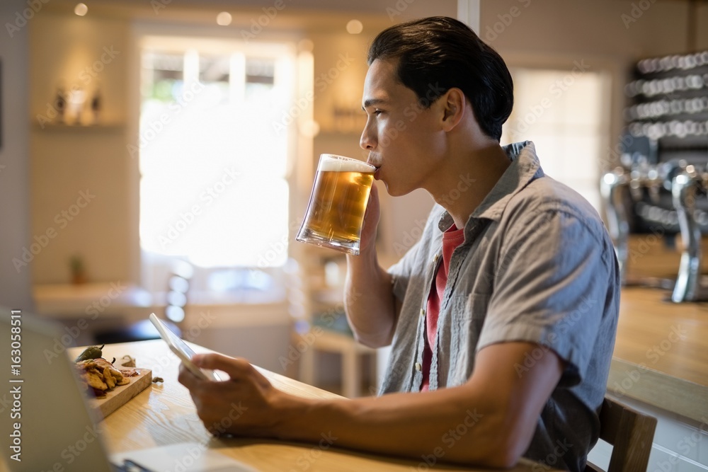 Man using digital tablet while having beer in restaurant