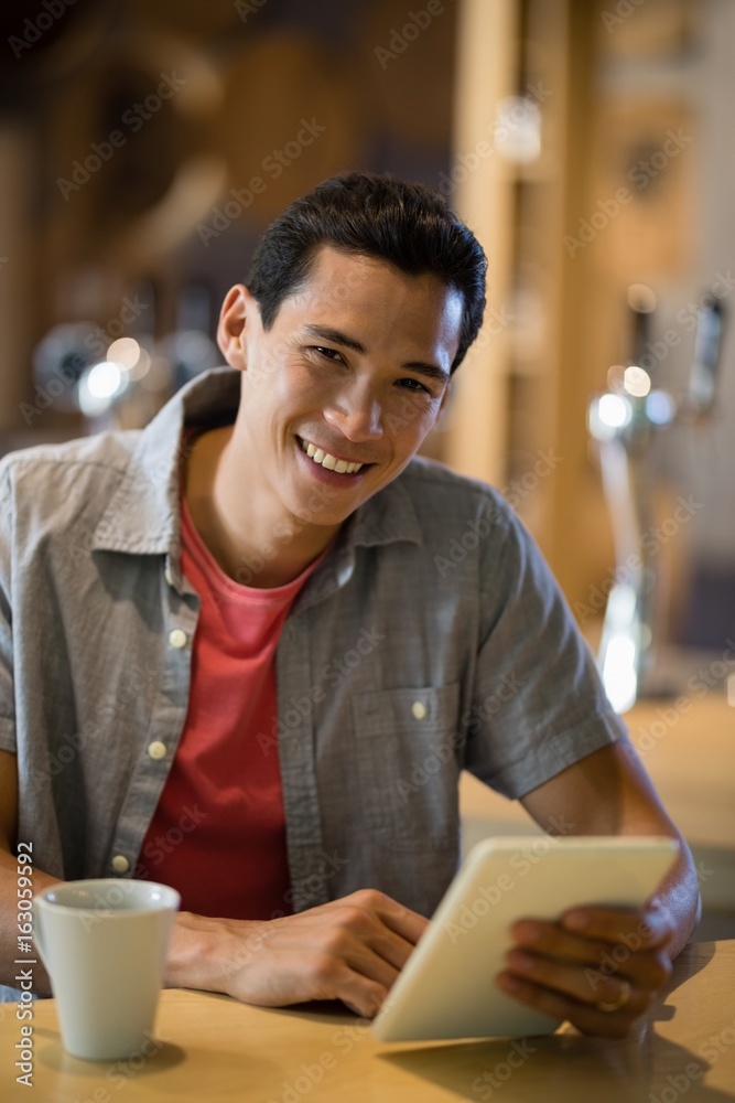 Man using digital tablet while having coffee in restaurant Man using digital tablet while having coffee in restaurant