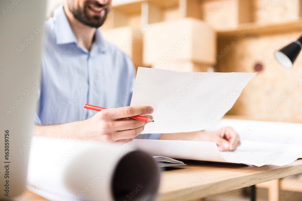 Youthful bearded man checking up his job at working place Youthful bearded man checking up his job at working place