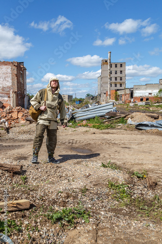 A man with a backpack in military uniform against the ruined building