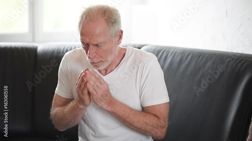 Senior man with allergy sneezing and blowing his nose
