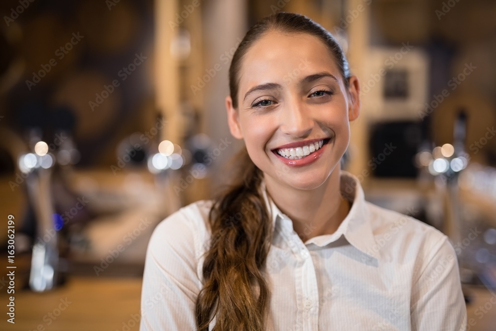 Smiling female bartender standing in bar Smiling female bartender standing in bar
