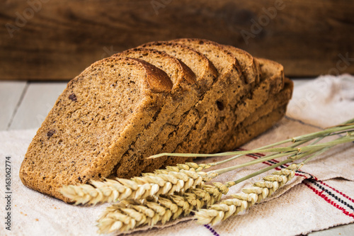 homemade bread and wheat on a light wooden background