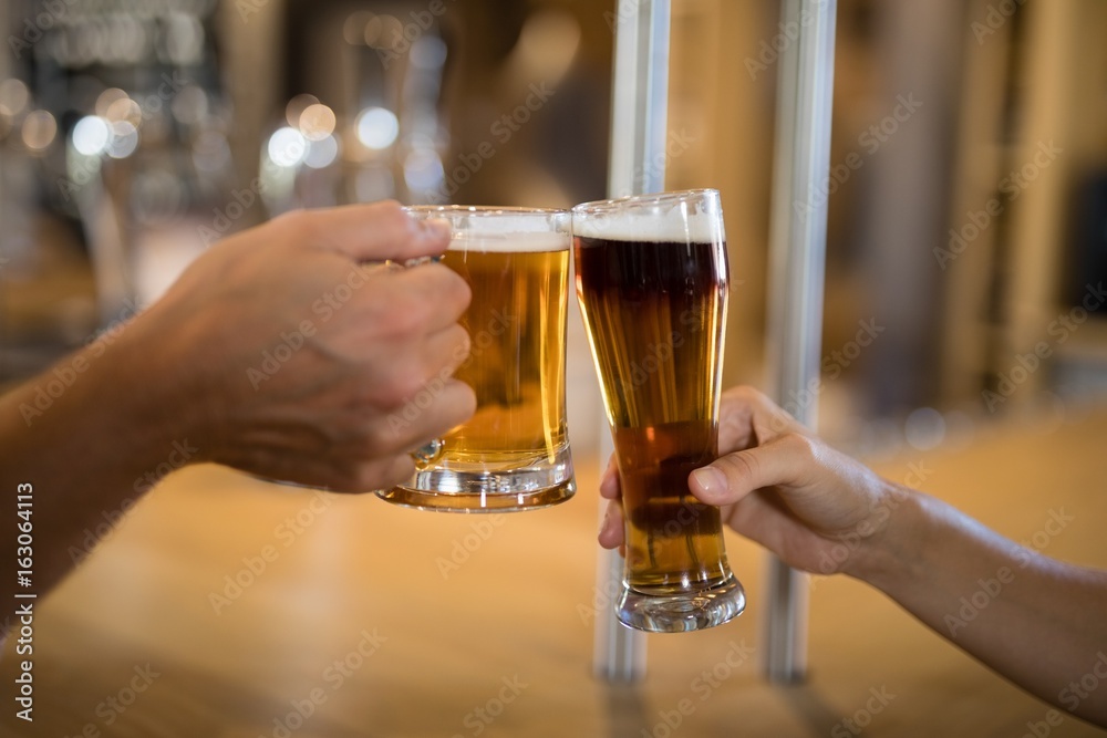 Couple toasting glass of beer at bar counter