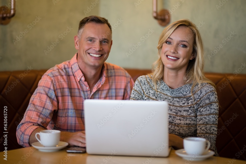 Happy couple using laptop while having coffee Happy couple using laptop while having coffee