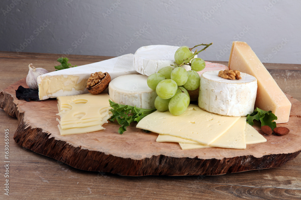 Cheese platter with different cheese on brown wooden plate